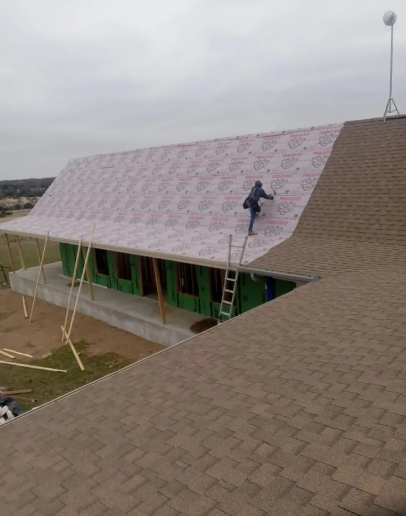 Worker preparing underlayment for a metal roof installation in Muleshoe